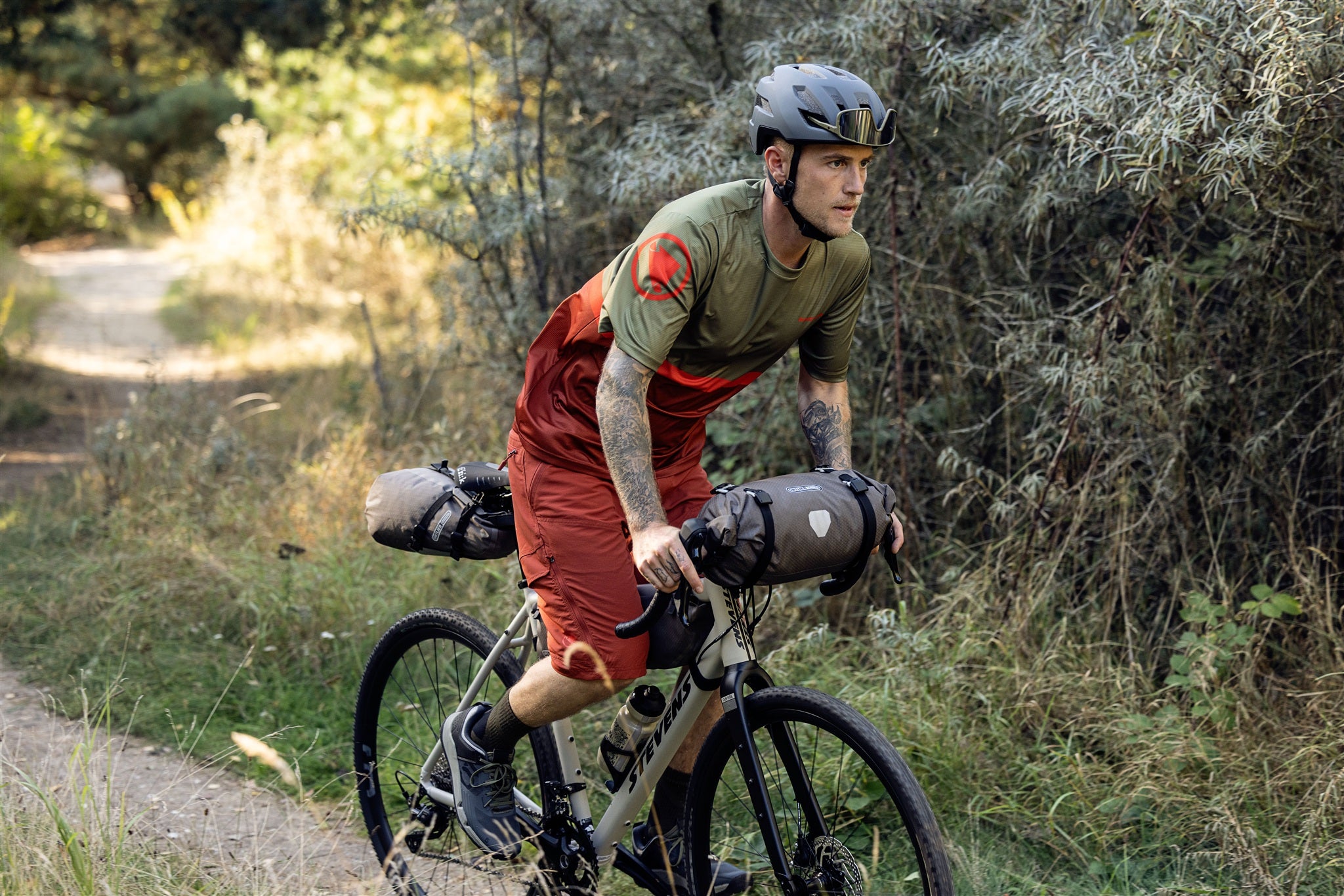 Ciclista fissa la borsa manubrio ORTLIEB Handlebar-Pack Flex color dark-sand su percorso sterrato