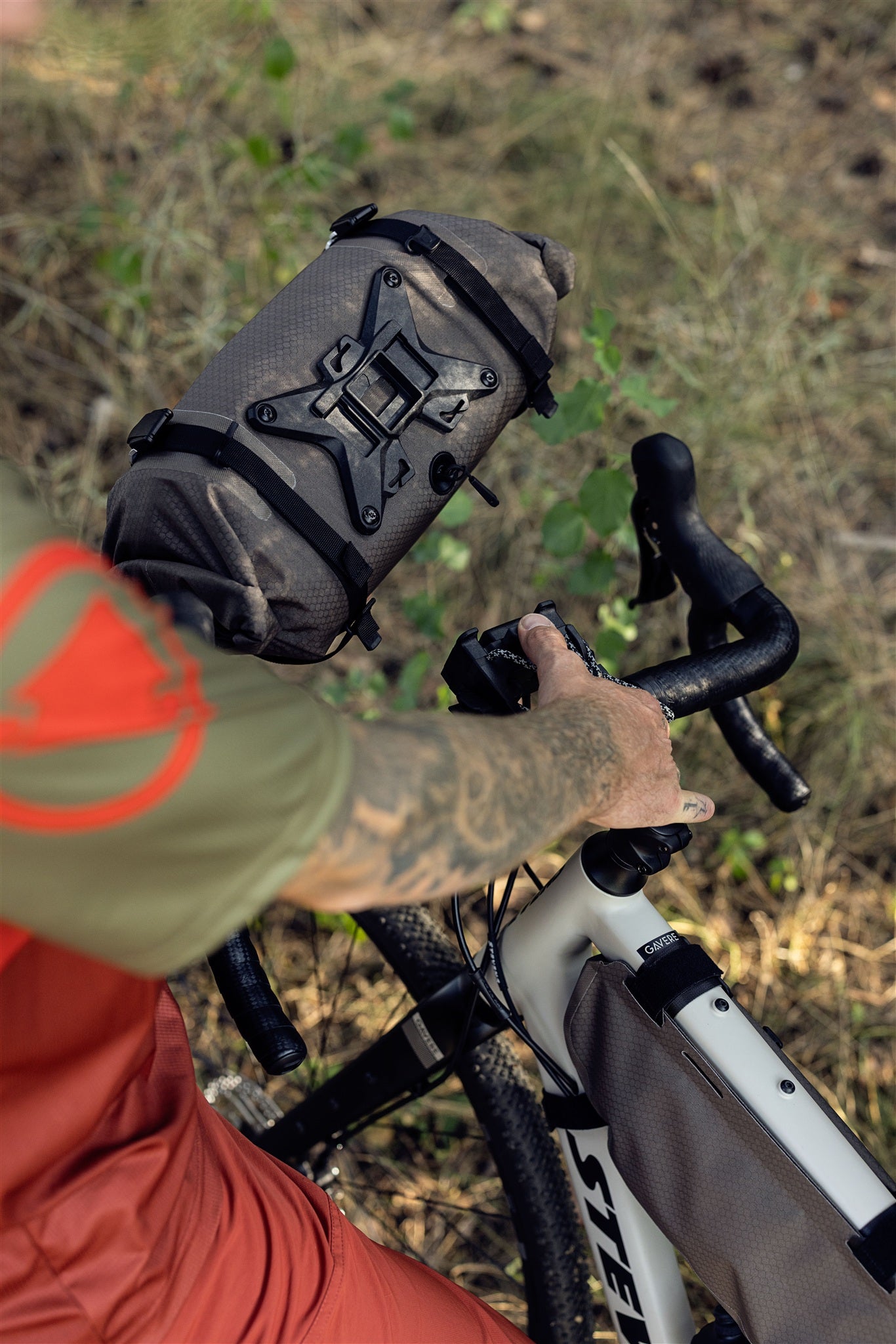 Ciclista con borsa da manubrio ORTLIEB Handlebar-Pack Flex color dark-sand su sentiero nel bosco