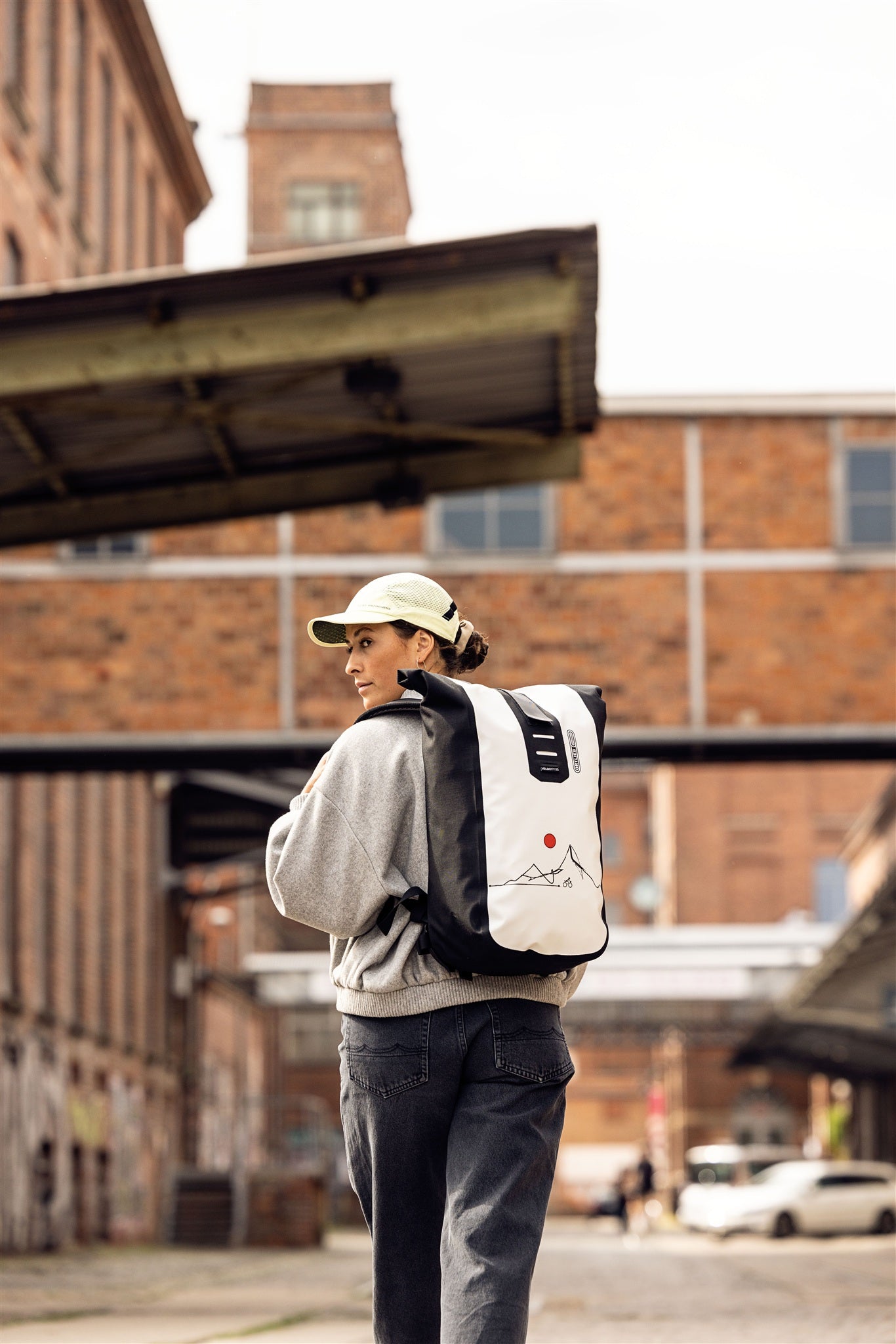 Donna con zaino ORTLIEB Velocity Design in area industriale con edifici in mattoni